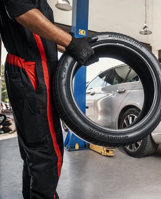 A Fit & Fix worker holding a car wheel. 